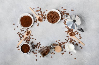 Kahve çekirdekleri ve öğütülmüş kahve, dokulu bir yüzeyde demleme aletleriyle güzelce düzenlenir. Sıcak ve davetkar bir kahve deneyimi uyandırır.