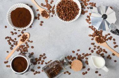 Kahve çekirdekleri ve öğütülmüş kahve, dokulu bir yüzeyde demleme aletleriyle güzelce düzenlenir. Sıcak ve davetkar bir kahve deneyimi uyandırır.