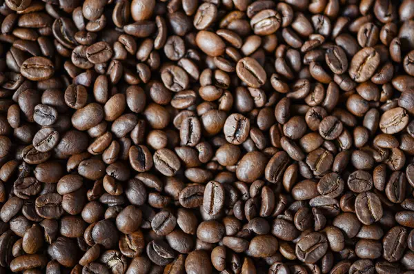 Kavrulmuş kahve çekirdeklerinin yakın plan görüntüsü, zengin dokular ve derin renkler sergileniyor, aşçılık uygulamaları için kahvenin doğal güzelliğini vurguluyor