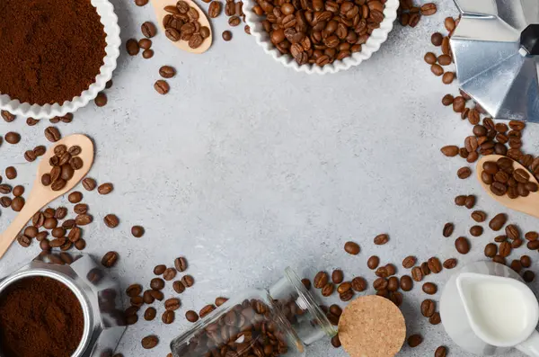 Kahve çekirdekleri ve öğütülmüş kahve, dokulu bir yüzeyde demleme aletleriyle güzelce düzenlenir. Sıcak ve davetkar bir kahve deneyimi uyandırır.