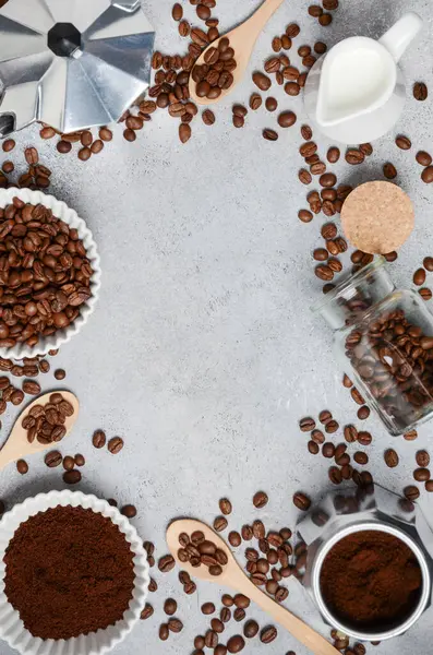 Kahve çekirdekleri ve öğütülmüş kahve, dokulu bir yüzeyde demleme aletleriyle güzelce düzenlenir. Sıcak ve davetkar bir kahve deneyimi uyandırır.