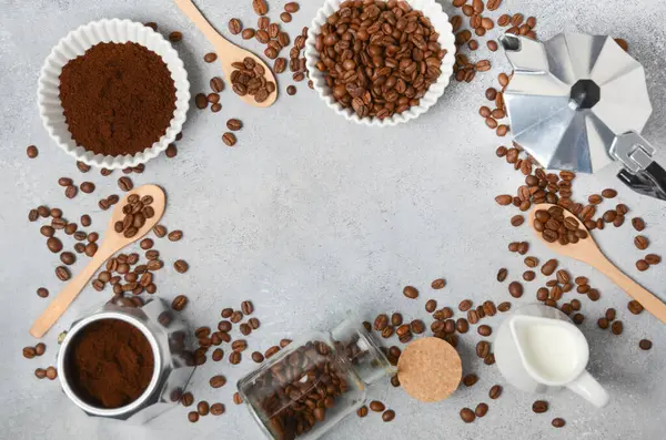 Kahve çekirdekleri ve öğütülmüş kahve, dokulu bir yüzeyde demleme aletleriyle güzelce düzenlenir. Sıcak ve davetkar bir kahve deneyimi uyandırır.