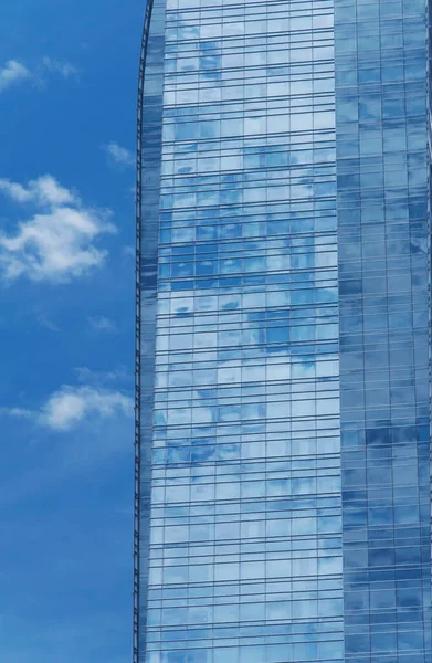 stock image a modern glass building rising above the city of los angeles california on a sunny blue sky day.