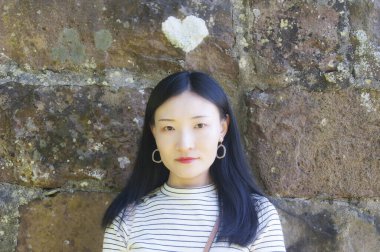 Connecticut 'ta kalp şeklinde bir liken büyüyen bir duvarın yanında Çinli bir kadın.. 