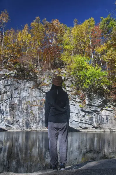 stock image a woman overlooking the fall foliage at the abandoned Becket Quarry in Massachusetts on a sunny day. 