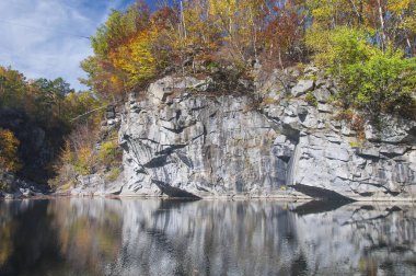 Güneşli bir günde Massachusetts 'teki terk edilmiş Becket Taş Ocağı' nda su ve sonbahar yaprakları..