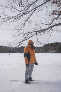 Torrington 'daki Burr göletinde kar üzerinde duran Asyalı bir adam kışın Connecticut' ta. 