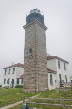 The historic landmark Beavertail lighthouse in Jamestown Rhode Island on a foggy day. clipart