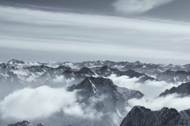 Garmisch-Partenkirchen Almanya 'sındaki Zugspitze tepesinden bulutlarla kaplı kara kaplı Wetterstein dağlarının siyah beyaz panoramik manzarası.