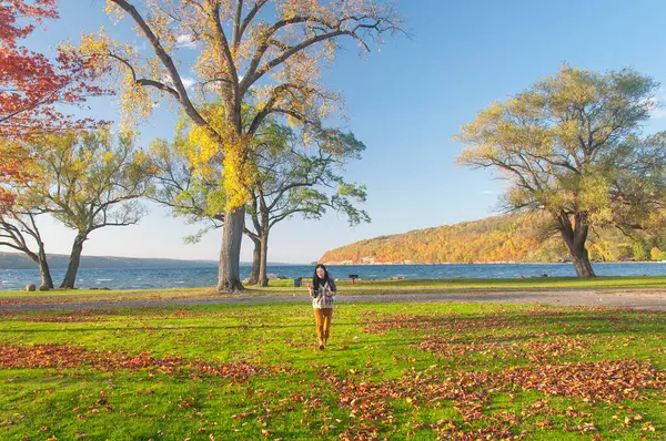 Çinli bir kadın Seneca Gölü 'ndeki Clute Park' ta yürüyor. Sonbaharda New York 'un kuzeyinde gün batımında..