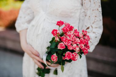 Arkaplanda çiçekli hamile bir karın.