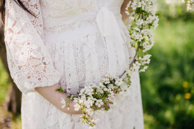 Arkaplanda çiçekli hamile bir karın.