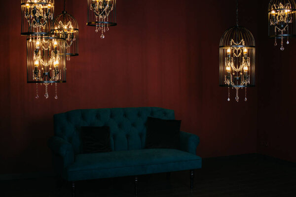 Темная комната с диваном, свечами и люстрами