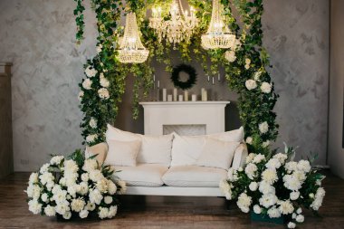 Beyaz bir kanepesi, avizeleri ve çiçekleri olan fotoğraf stüdyosu. Fotoğraf stüdyosu arka planı