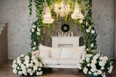 Beyaz bir kanepesi, avizeleri ve çiçekleri olan fotoğraf stüdyosu. Fotoğraf stüdyosu arka planı