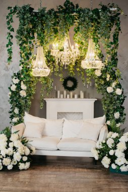 Beyaz bir kanepesi, avizeleri ve çiçekleri olan fotoğraf stüdyosu. Fotoğraf stüdyosu arka planı