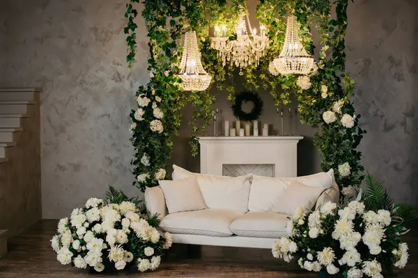 Photo studio location with white sofa, white flowers, stairs, fireplace, chandeliers and candles