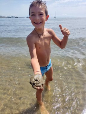 Küçük çocuk oynuyor ve dalgaların tadını çıkarıyor.