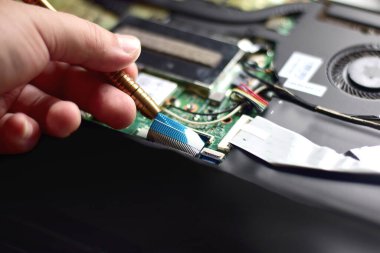 Bir bilgisayar tamircisi, ana kart bağlantı kablosunu bilgisayarın ana kartından çıkarmak için tornavida kullanıyor..