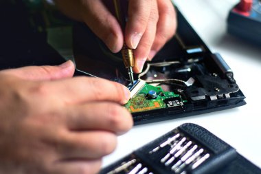 Bir bilgisayar tamir teknisyeni, bir bilgisayar anakartındaki cihazı çıkarmak için tornavida kullanıyor..