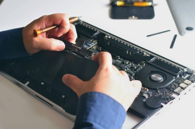 Bilgisayar teknisyeni dizüstü bilgisayardan pil çıkarıyor