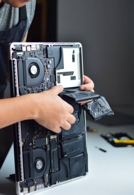 Bilgisayar teknisyeni dizüstü bilgisayardan pil çıkarıyor