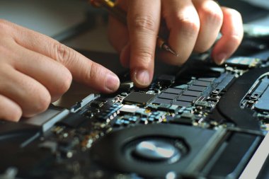 Bilgisayar teknisyeni bir dizüstü bilgisayar anakart tamircisi masasındaki arızaları bulmak için IC sayacını kullanıyor. Modern teknolojiyi kullanarak tahta onarımı