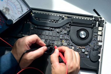 Bilgisayar teknisyeni bir dizüstü bilgisayar anakart tamircisi masasındaki arızaları bulmak için IC sayacını kullanıyor. Modern teknolojiyi kullanarak tahta onarımı