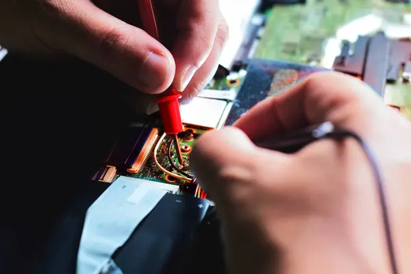 Bilgisayar teknisyeni bir dizüstü bilgisayar anakart tamircisi masasındaki arızaları bulmak için IC sayacını kullanıyor. Modern teknolojiyi kullanarak tahta onarımı