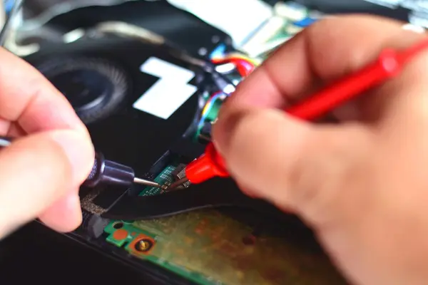 Bilgisayar teknisyeni bir dizüstü bilgisayar anakart tamircisi masasındaki arızaları bulmak için IC sayacını kullanıyor. Modern teknolojiyi kullanarak tahta onarımı