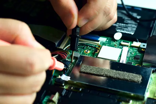 Bilgisayar teknisyeni bir dizüstü bilgisayar anakart tamircisi masasındaki arızaları bulmak için IC sayacını kullanıyor. Modern teknolojiyi kullanarak tahta onarımı