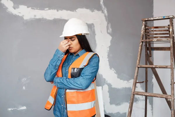 A young South Asian construction worker rubs her sinuses in pain, headache High quality photo