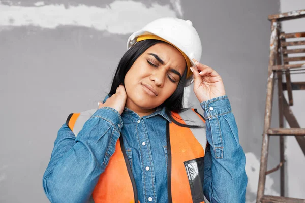 A young Indian construction worker holds her neck in pain from workplace injury. High quality photo