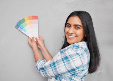 An Indian woman contemplates paint swatches on newly renovated wall. High quality photo