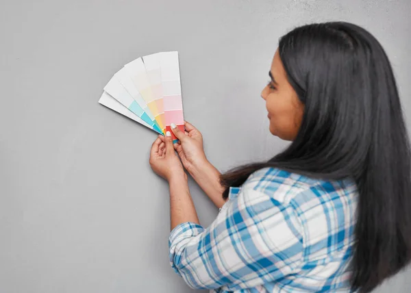 An Indian woman contemplates paint swatches on newly renovated wall. High quality photo