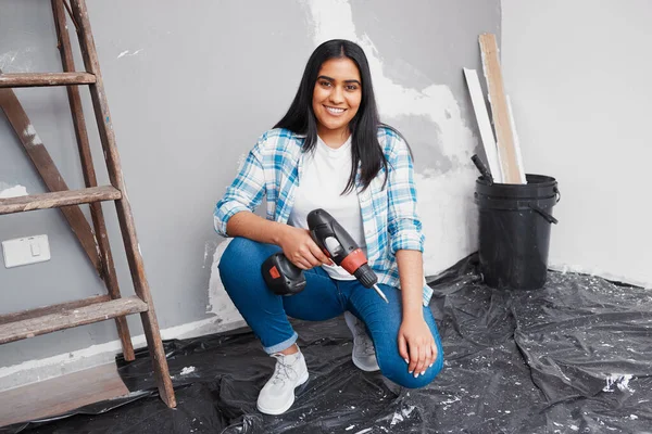 A young woman crouches on the floor holding screwdriver doing home DIY renovation. High quality photo