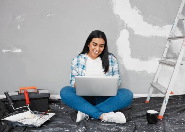 A young woman researches home DIY ideas and how-to guides while renovating. High quality photo