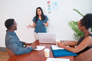 Indian woman leads meeting in the office boardroom, gesture explain to colleagues. High quality photo
