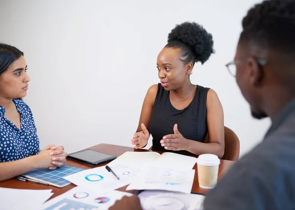 Black woman executive discusses financial results around boardroom office table. High quality photo
