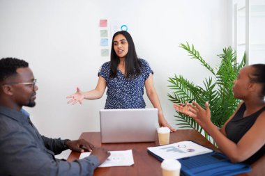 Indian woman leads meeting in the office boardroom, gesture explain to colleagues. High quality photo