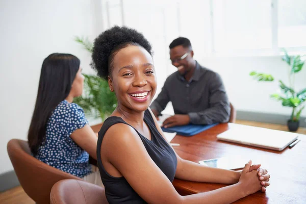 Black business woman smiles turns to camera at conference table with colleagues. High quality photo