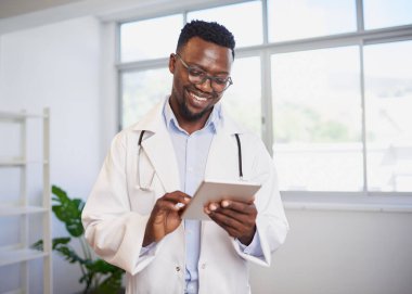 Parlak ofiste dijital tablet kullanan genç bir siyahi doktorun portresi. Yüksek kalite fotoğraf