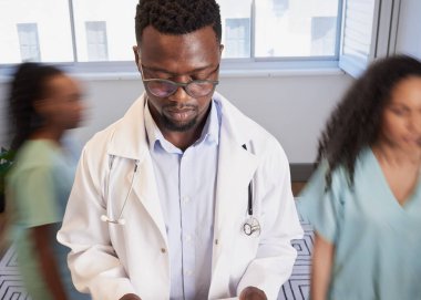 Siyahi erkek doktor hemşireler aceleyle geçerken hareketsiz duruyor, hareket bulanıklığı kliniği. Yüksek kalite fotoğraf