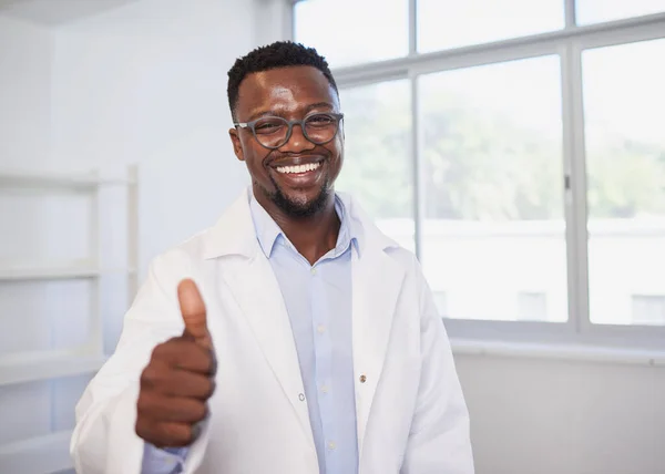 Portrait of smiling Black doctor giving thumbs up in modern clinic. High quality photo