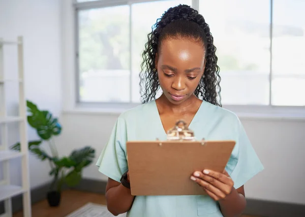 Young Black healthcare professional fills in patient information on clipboard. High quality photo