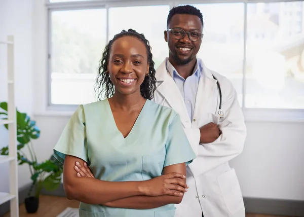 Portrait of two Black doctors, man and woman arms folded posing in clinic. High quality photo