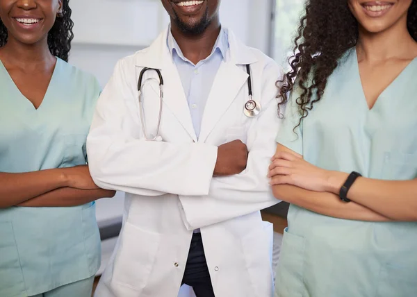 Three medical healthcare professionals stand in a row smiling arms folded. High quality photo