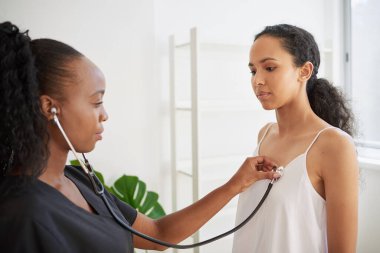 Siyahi kadın doktor sağlık kontrolünde hastaların kalp atışlarını dinler. Yüksek kalite fotoğraf