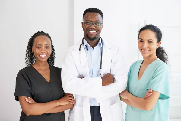 Three medical healthcare professionals stand in a row smiling arms folded. High quality photo