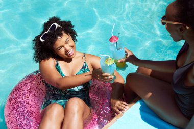 İki arkadaş havuzda keyifli keyifli kokteyller içiyor, şişme yüzüyorlar. Yüksek kalite fotoğraf